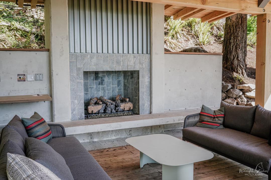 a concrete and tile fireplace surrounded with comfortable seating